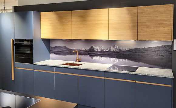 Ansicht der modernen Küche mit Küchenrückwand aus Glas mit Spiegelung des Dreigestirns als Motiv.