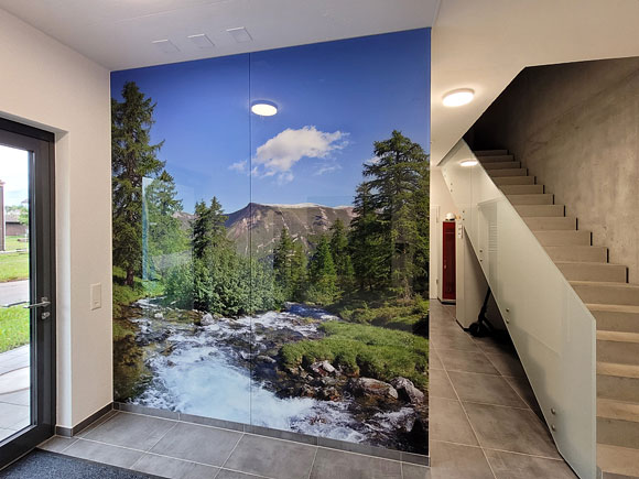 Das grosse Wandbild einer Landschaft mit Bergbach und lichtem Lärchenwald als Motiv.